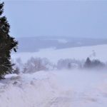 Zima, zaśnieżona droga w tle zabudowania - fot. KMP Nowy Sącz