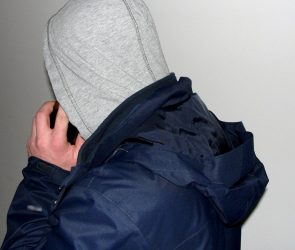 mężczyzna w bluzie w kapturem na głowie rozmawia przez telefon komórkowy