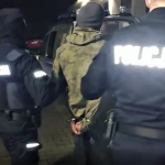 Umundurowani policjanci prowadzą sprawcę do radiowozu - fot. KMP Nowy Sącz