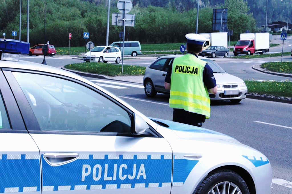 kontrola drogowa - policjant przy radiowozie, w tle samochody