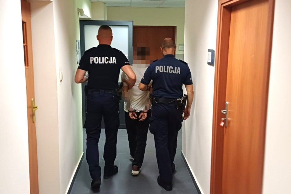 umundurowani policjanci prowadzą zatrzymanego mężczyznę korytarzem komisariatu